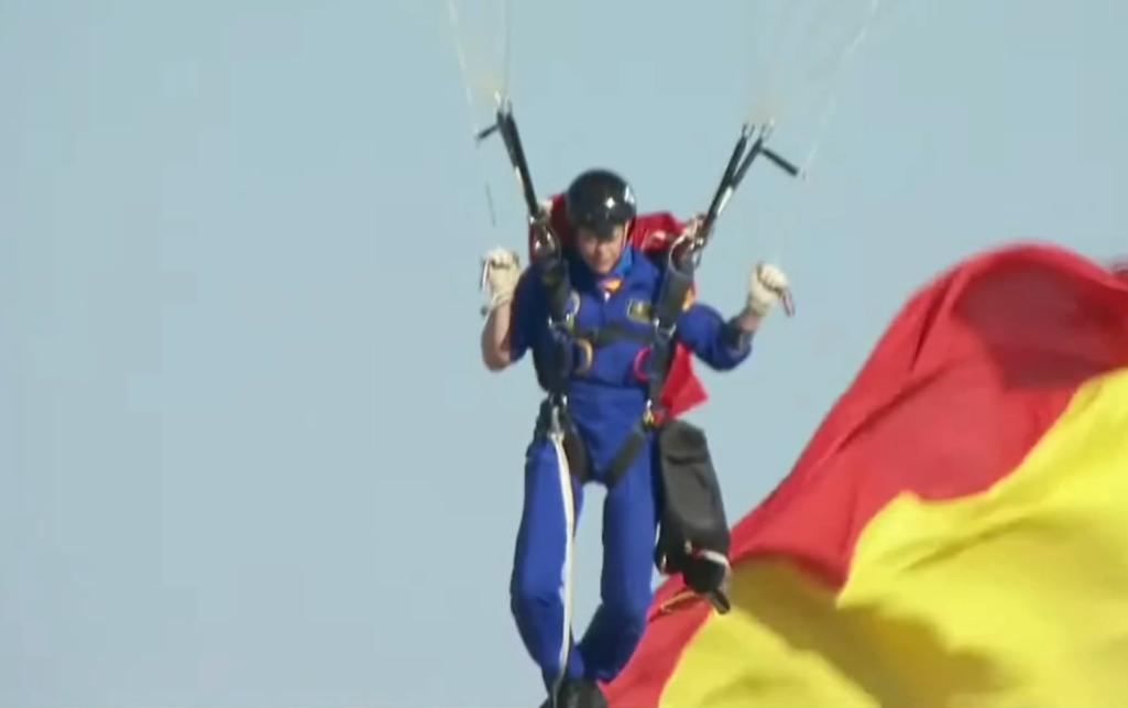 La cabo Maria del Carmen Gomez Hurtado aterriza en estos momentos con la bandera de 54 metros, desde 1.000 metros de altura. Es la primera mujer paracaidista que ha desplegado la bandera el 12 de octubre.
