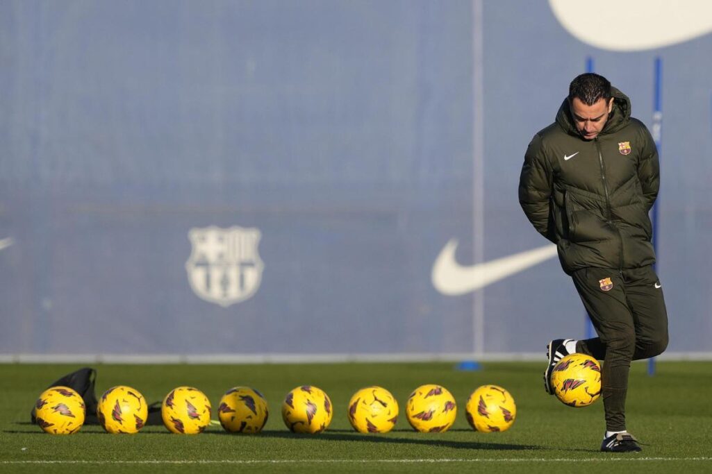 Xavi juguetea con un balon mientras espera la llegada de los futbolistas al entrenamiento.