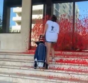 Momento en el que uno de los activistas de Climaximo mancha con pintura roja la fachada de la sede Redes Energeticas Nacionales